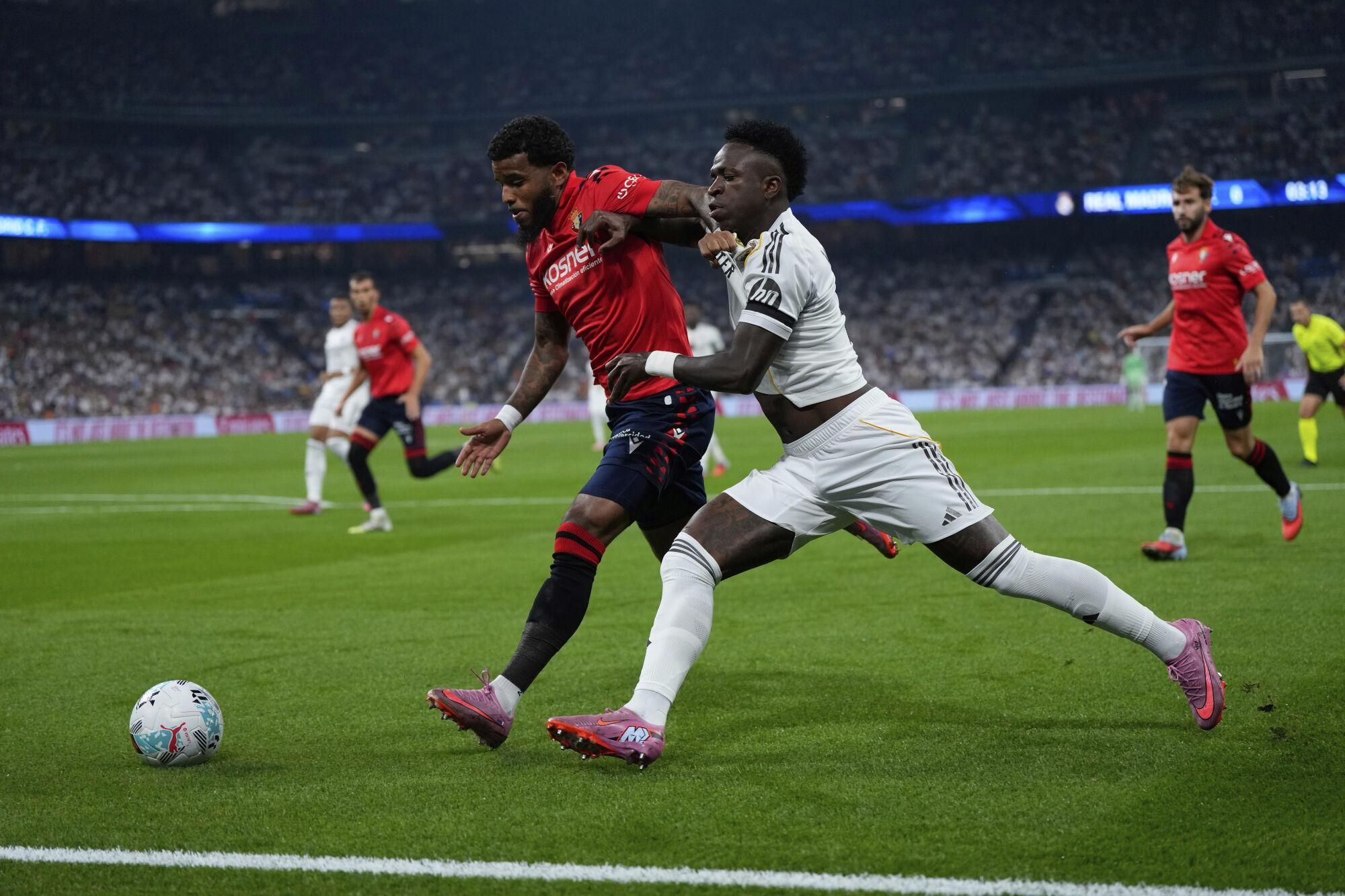 Osasuna's Valentin Rosier, left, and Real Madrid's Vinicius Junior fight for the ball during the La Liga soccer match between Real Madrid and Osasuna in Madrid, Spain, Tuesday, Aug. 19, 2025. (AP Photo/Manu Fernandez)