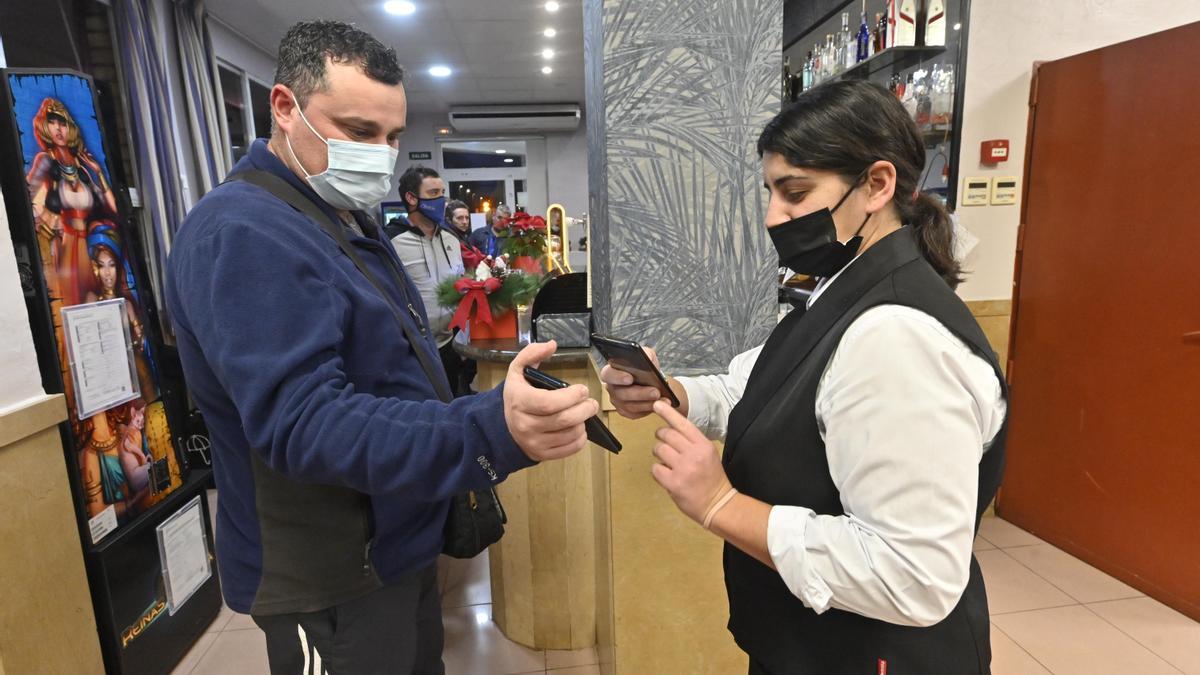 Un cliente muestra el pasaporte covid a la llegada a un restaurante