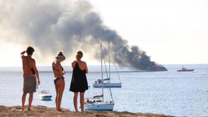 Tres personas observan el jueves el incendio del ‘Aria SF’. | VICENT MARÍ