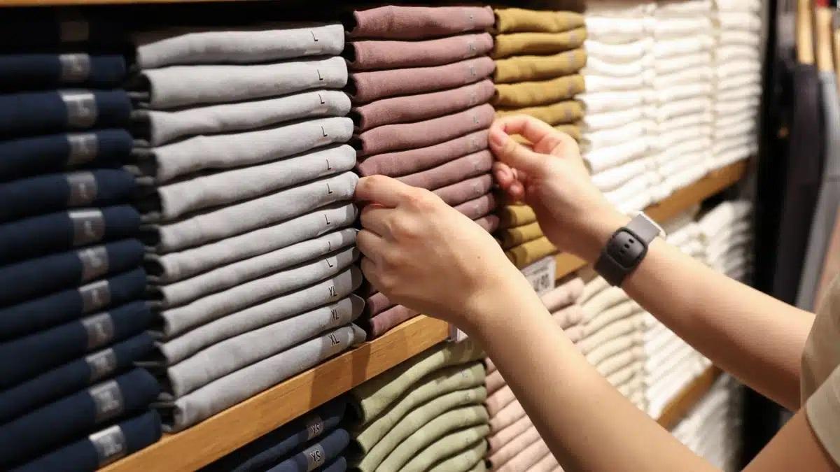 Una dependienta coloca la ropa en una tienda de moda.