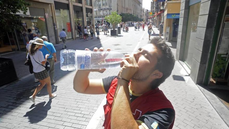 Un joven se hidrata para soportar el calor de la calle.