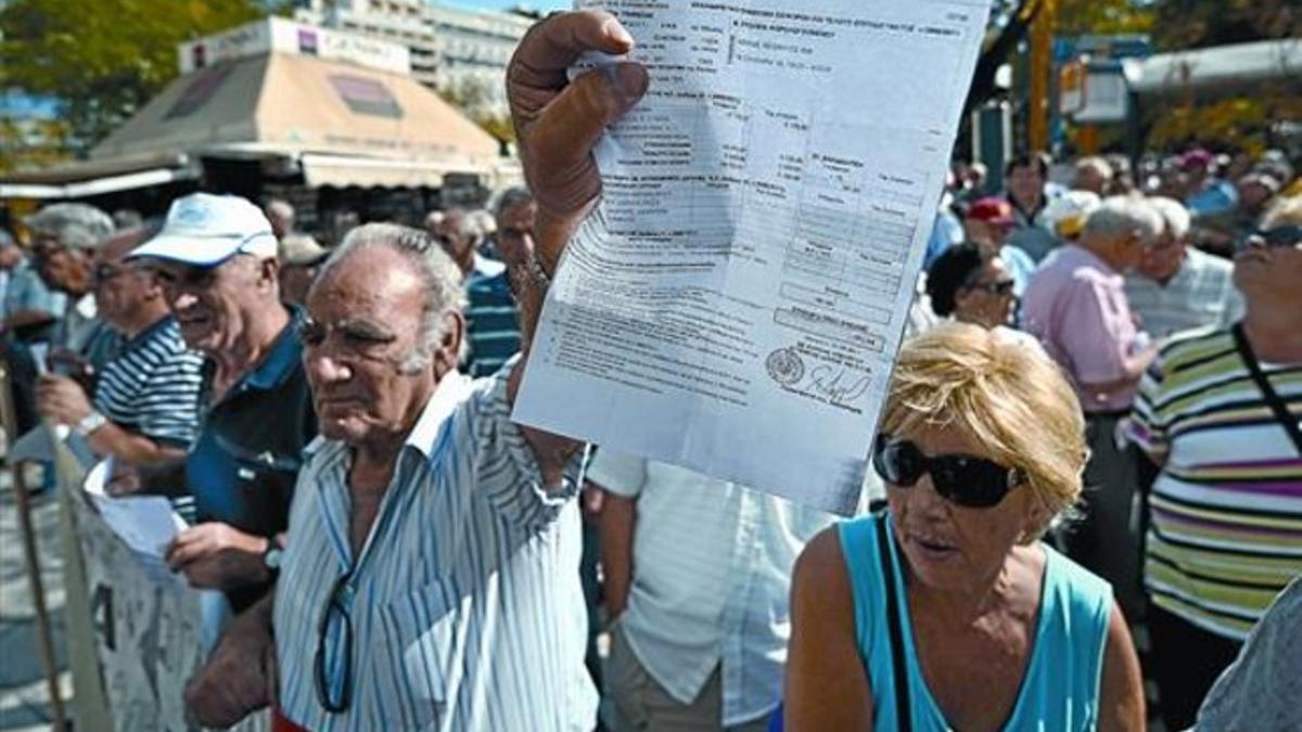 Un pensionista griego muestra el recibo de un impuesto durante una manifestación ante el Ministerio de Finanzas en Atenas.