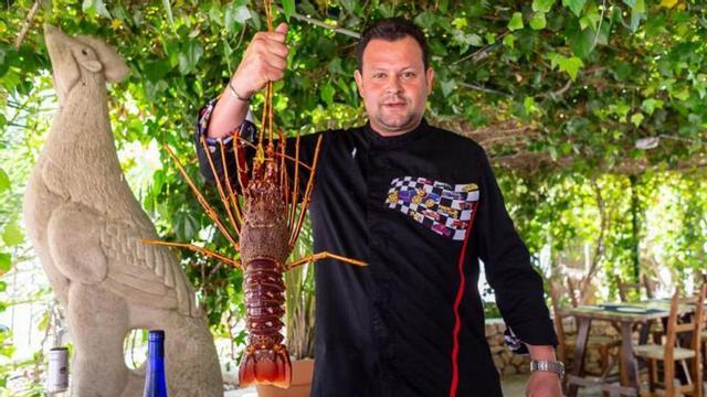 El propietario del restaurante muestra una de la s langostas que sirven. | DI