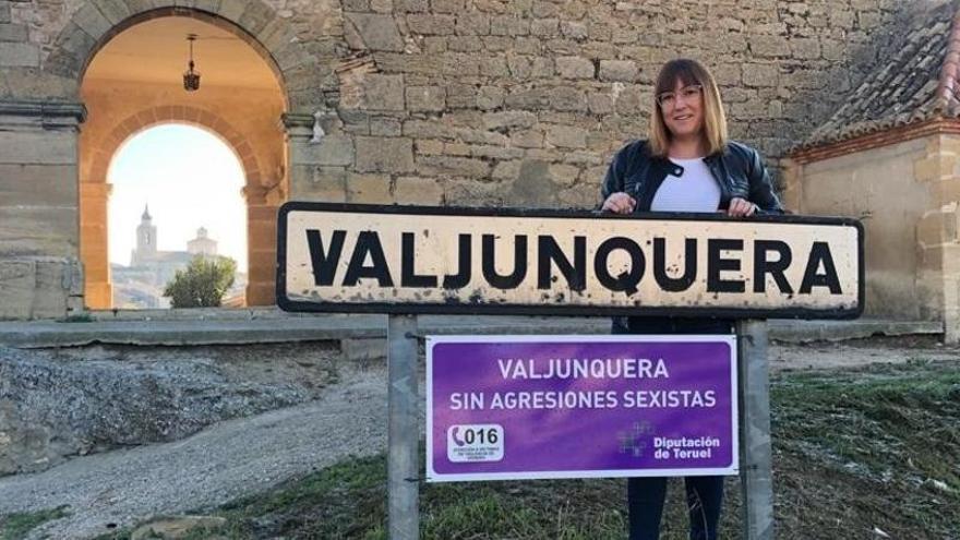 Susana Traver, diputada de Educación, Bienestar Social e Igualdad de la DPT, junto al cartel instalado en Valjunquera.