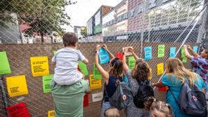 Familias de las escuela Auditori de Barcelona cuelgan carteles de protesta durante el primer día de clase.