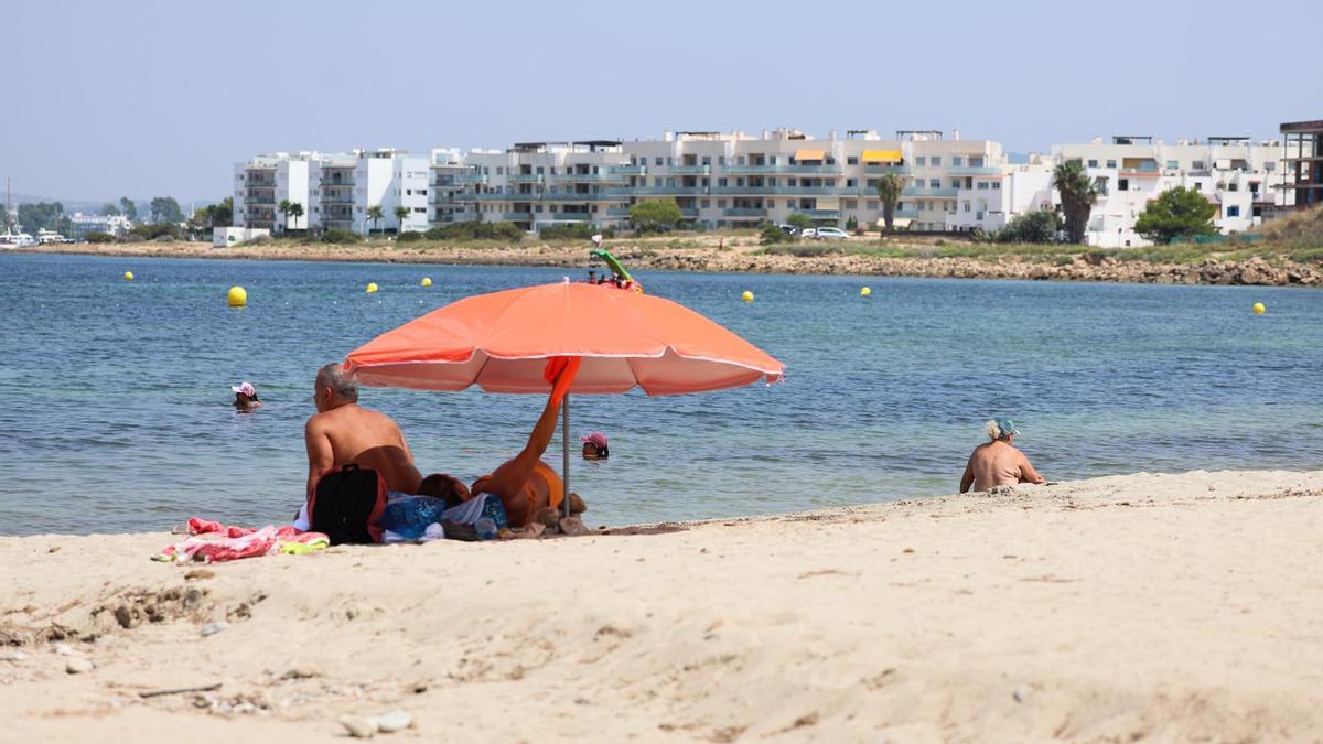 Unos bañistas con su propia sombrilla en una playa de Ibiza.