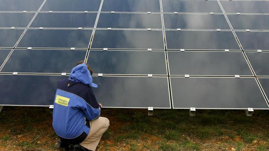 Un técnico revisa unas placas solares en una planta fotovoltaica.