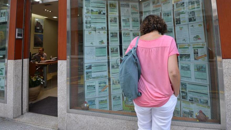 Una joven consultando el escaparate de una inmobiliaria.