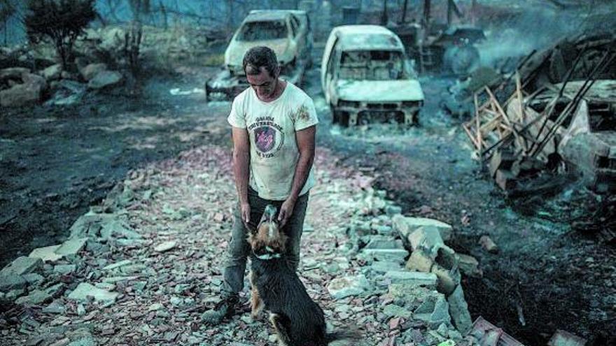 Isaac y uno de sus perros,tras volver a su nave de coches,arrasada por el incendio de Verín.  