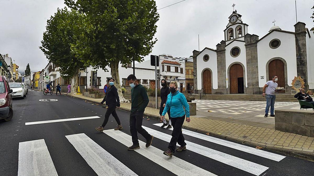 Varios peatones cruzan la calle principal de Valleseco con la iglesia al fondo. | | ANDRÉS CRUZ