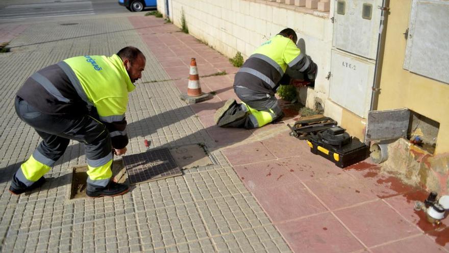 Dos operarios supervisan un contador de agua en una calle de Cartagena para ver si está adulterado.