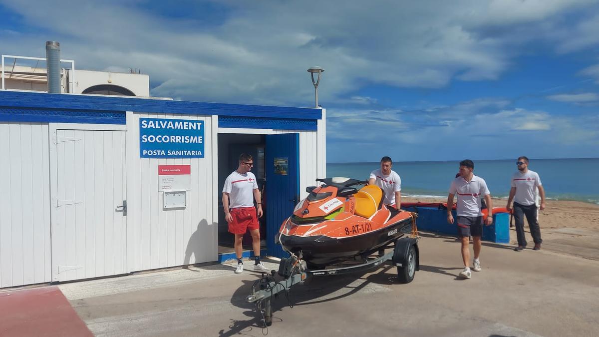 Varios socorristas de Cruz Rojan guardan la moto acuática en la playa de Tavernes