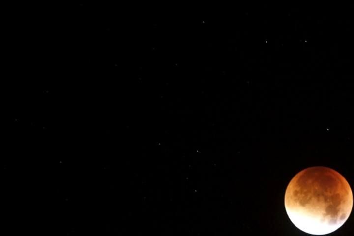 Stars are seen while the moon turns orange during a total "supermoon" lunar eclipse in Ronda