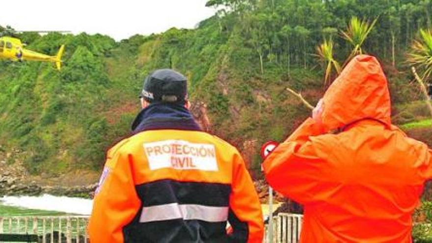 Efectivos de Protección Civil observan el despegue del helicóptero del 112-Asturias. | braulio fernández