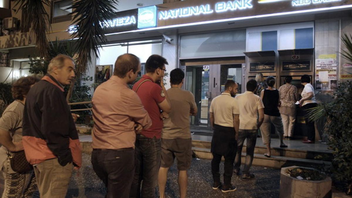 Ciudadanos griegos hacen cola ante el cajero del Banco Nacional de Grecia, en Atenas, esta madrugada.