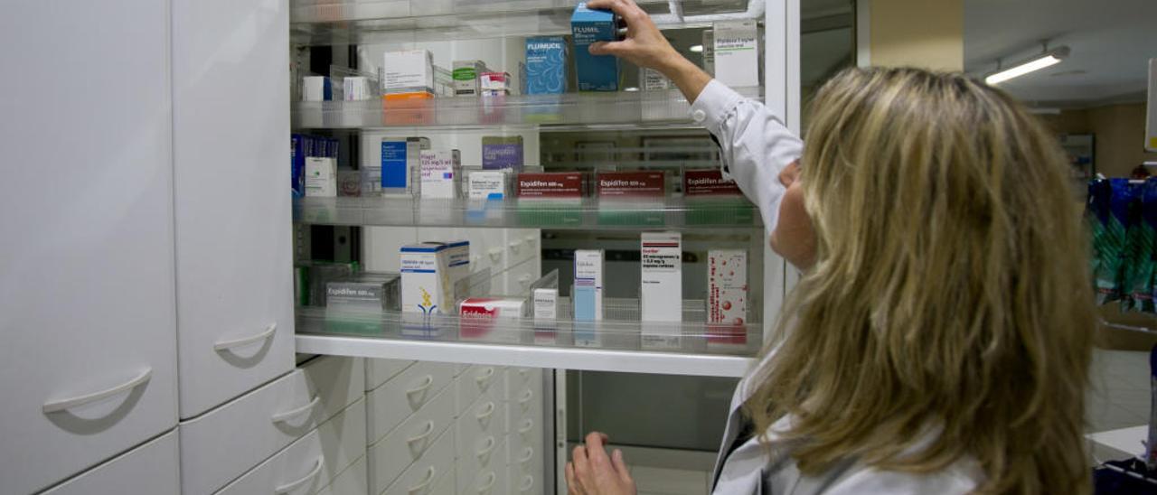 Una boticaria busca un medicamento en el almacén de una farmacia.