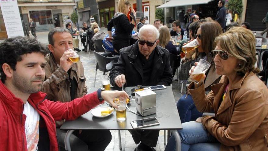 Varios clientes degustando una tapa con cañas en una terraza del centro.