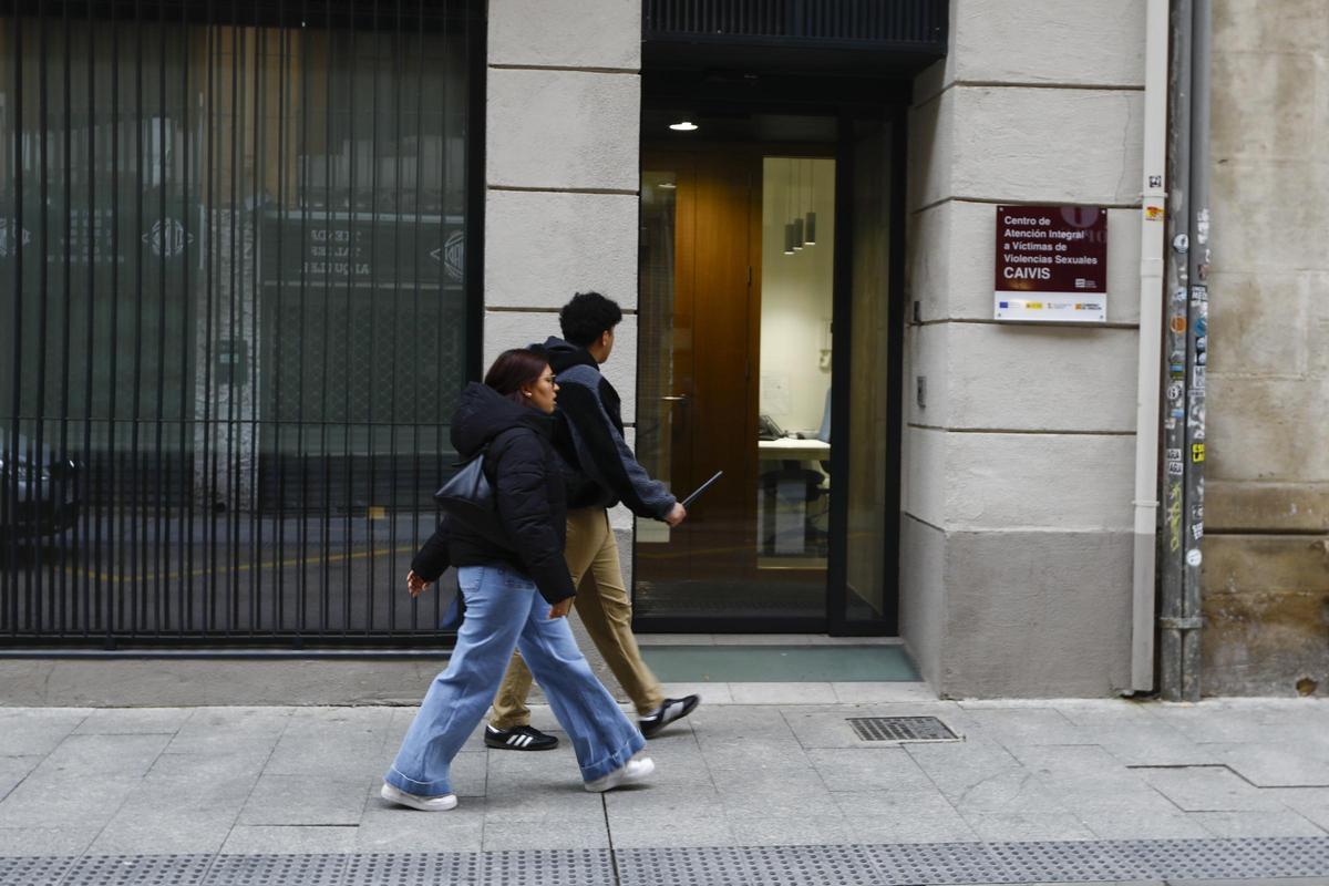 Dos jóvenes pasan por delante de la puerta del centro de atención a víctimas de Zaragoza.