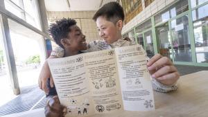 Dos alumnos del instituto escuela Rafael Alberti muestran los folletos informativos que han elaborado para ayudar a las familias migranteso