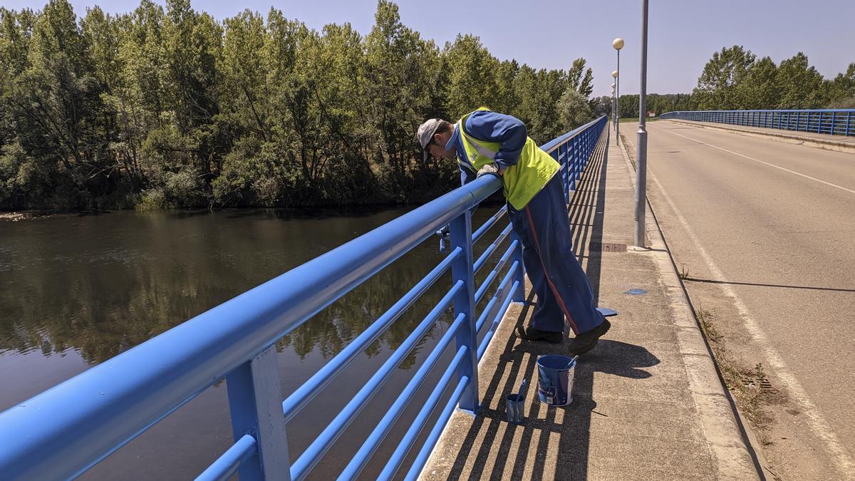 Repasando la segunda capa de pintura con brocha en las protecciones de la margen izquierda del puente.