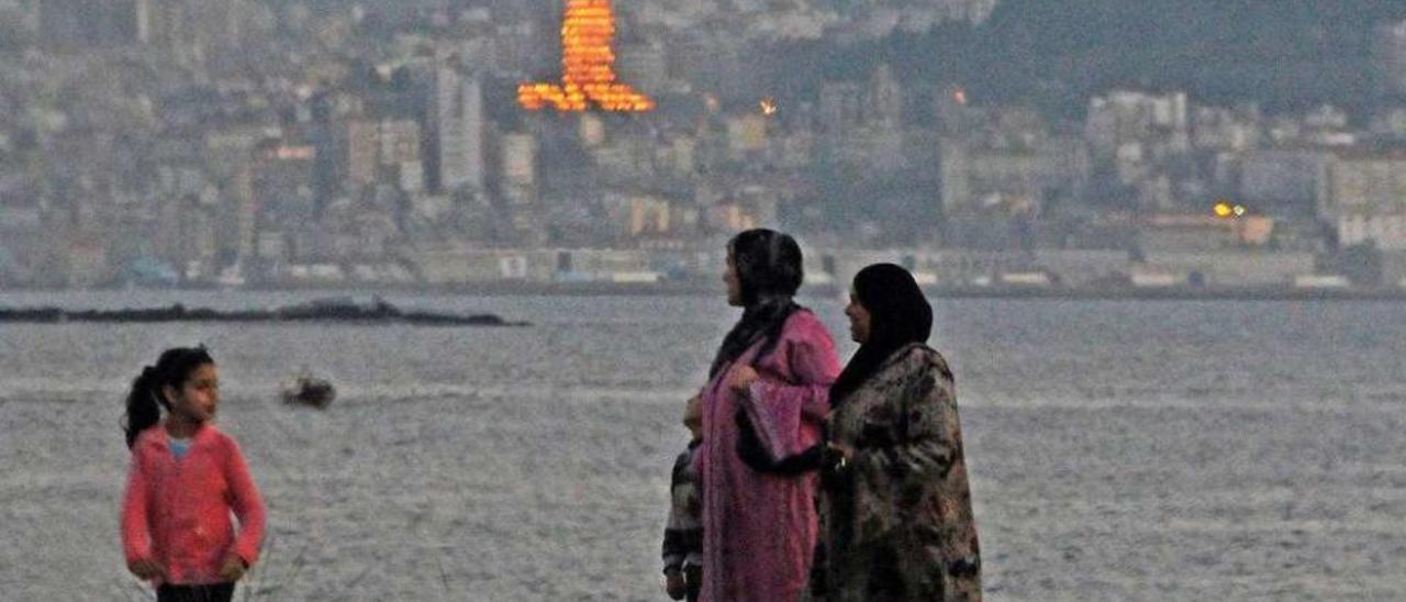 Dos mujeres inmigrantes pasean junto a una niña por la playa canguesa de Rodeira. // Gonzalo Núñez