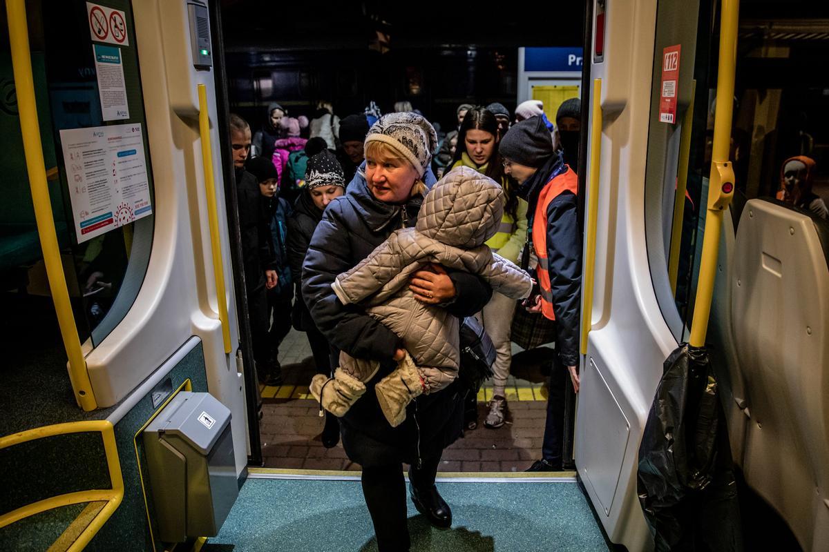 Una mujer procedente de Ucrania con un niño en brazos sube a un tren para proseguir viaje, en la estación de tren de Przemysl.