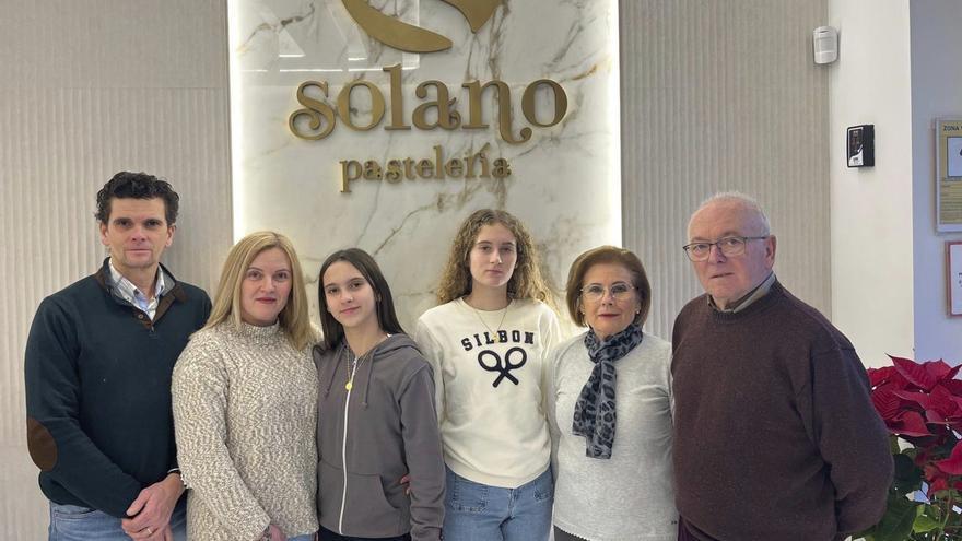 Sonia Solano y Agustín Romero posan con su familia en el local de Pastelería Solano, en Aguilar. | G. ALBORNOZ