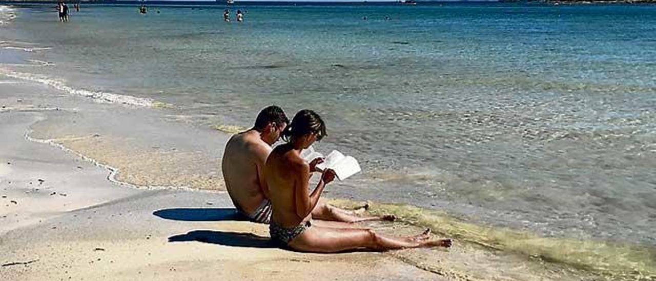 Bañistas leyendo en la playa de es Carbó.