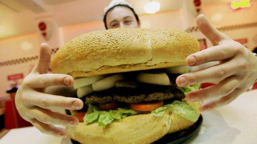 Un camarero muestra una hamburguesa gigante.