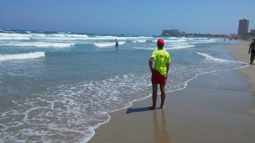 Un socorrista controla a un bañista con bandera roja.