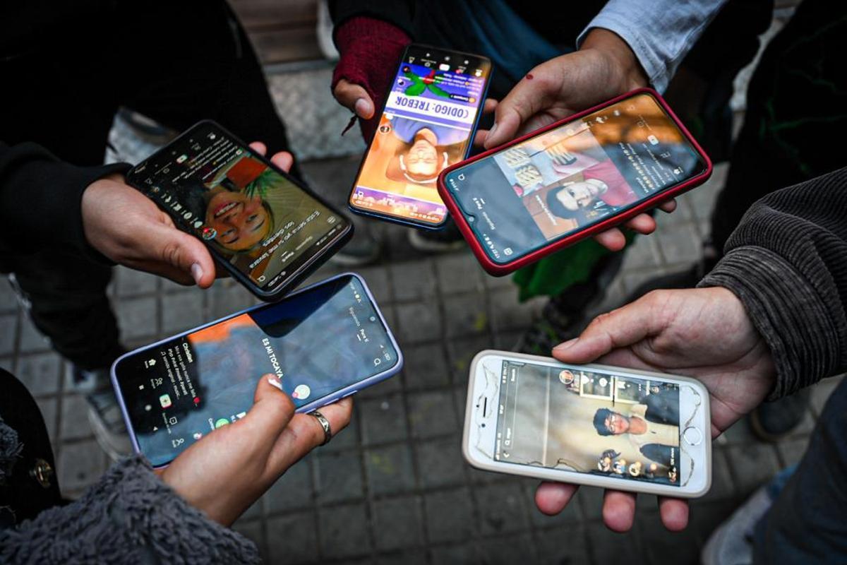 Un grupo de jóvenes miran vídeos de TikTok desde sus móviles.