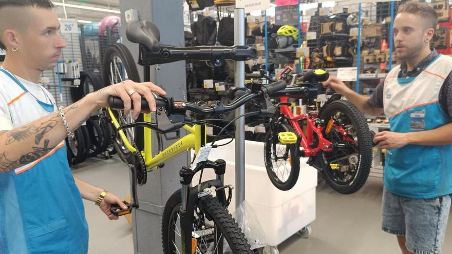 Jorge Corral (a la izquierda) y Juan Sánchez, con unas bicicletas, en la tienda de Lugones donde trabajan. | L. R.