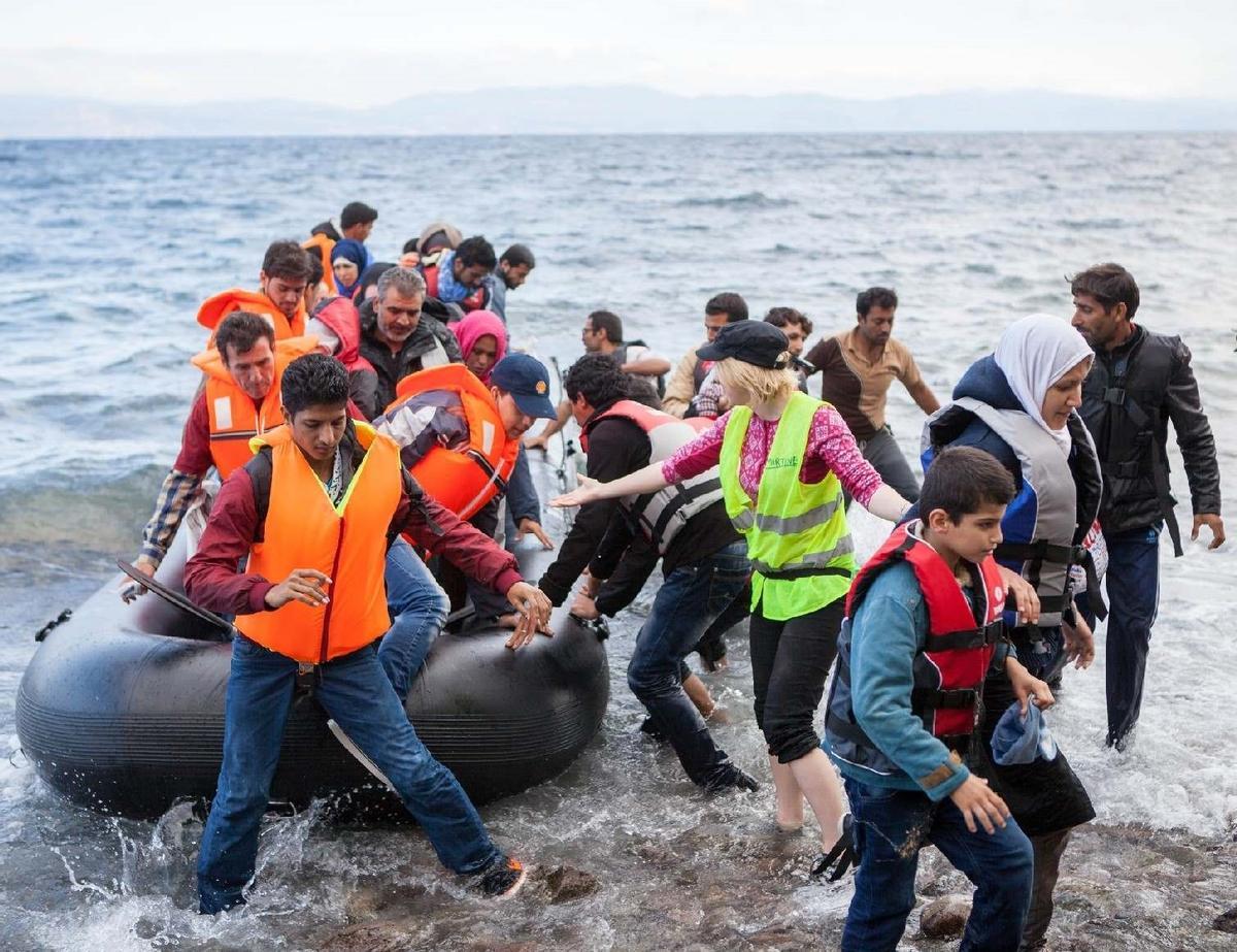 Migrantes llegando a la costa en una barca hinchable