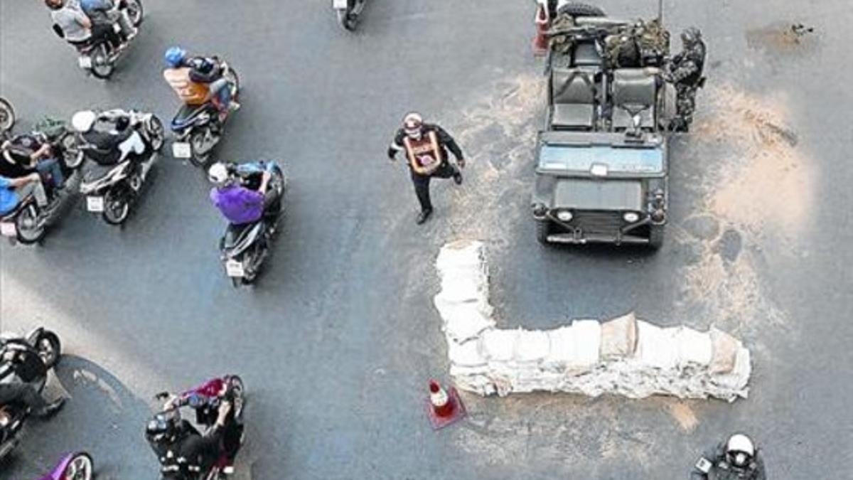 Unos motociclistas pasan junto a un vehículo del Ejército en una intersección del centro de Bangkok, ayer.