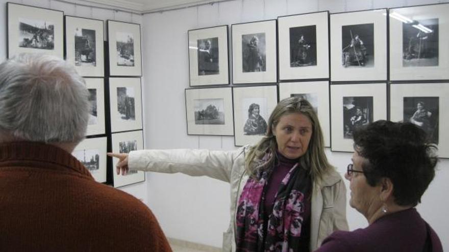 La concejala de Cultura de Camarzana, M. Jesús Castaño (centro), explica a dos visitantes la  muestra fotográfica.