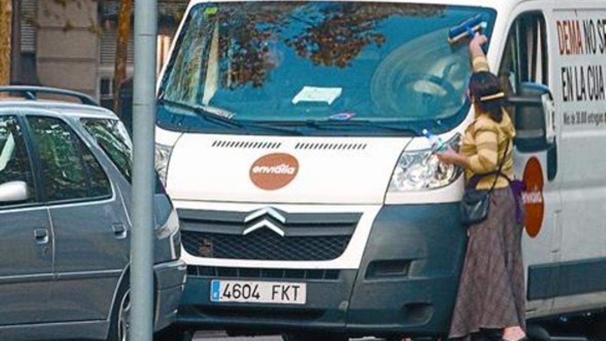 Una joven rumana limpia un parabrisas en un cruce del paseo de Sant Joan con la Diagonal, el viernes.