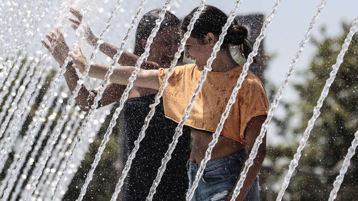 Unas chicas se refrescan en una fuente de la ciudad de Valencia