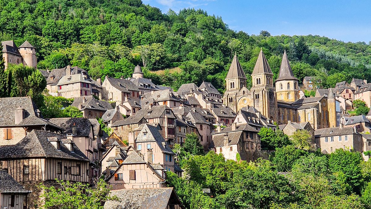 Vista panorámica de Conques, en Aveyron, con sus casas de piedra y la abadía románica de Sainte-Foy rodeadas de vegetación