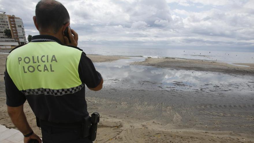 Un agente de Policía observa la playa de la Albufereta anegada tras las lluvias