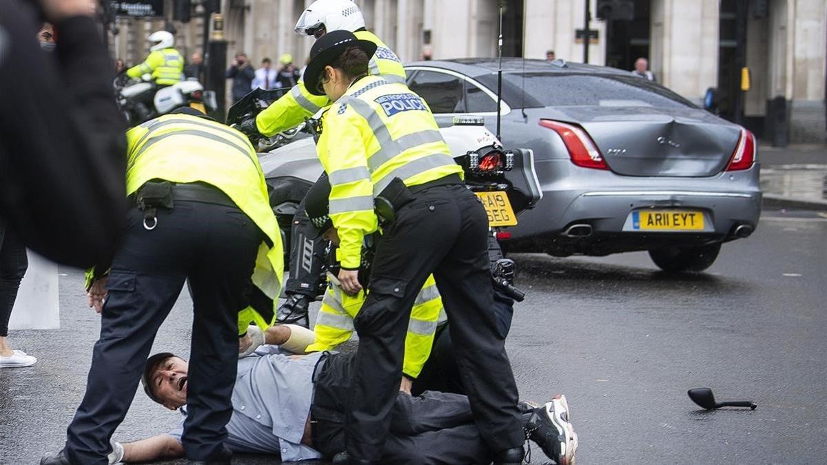 Policías británicos detienen a un manifestante que ha porvocado un accidente en el que se ha visto involucrado el coche del primer ministro Boris Johnson, el 17 de junio del 2020