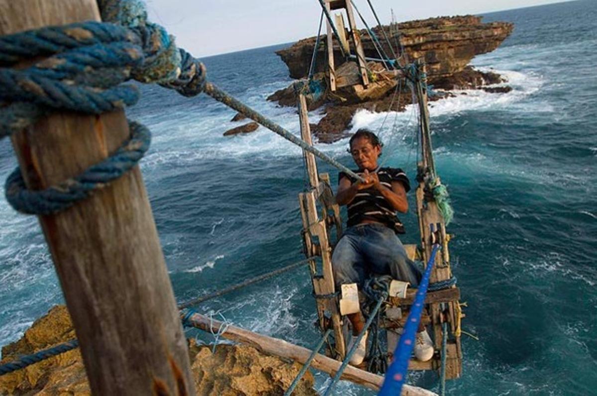 Un pescador maniobrant en un telefèric, construït per ell mateix, per travessar el mar a Timang (Indonèsia).