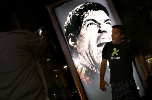 People use their mobile devices to take pictures of an advertising placard showing Uruguay's striker Luis Suarez flashing his teeth at Copacabana beach in Rio de Janeiro