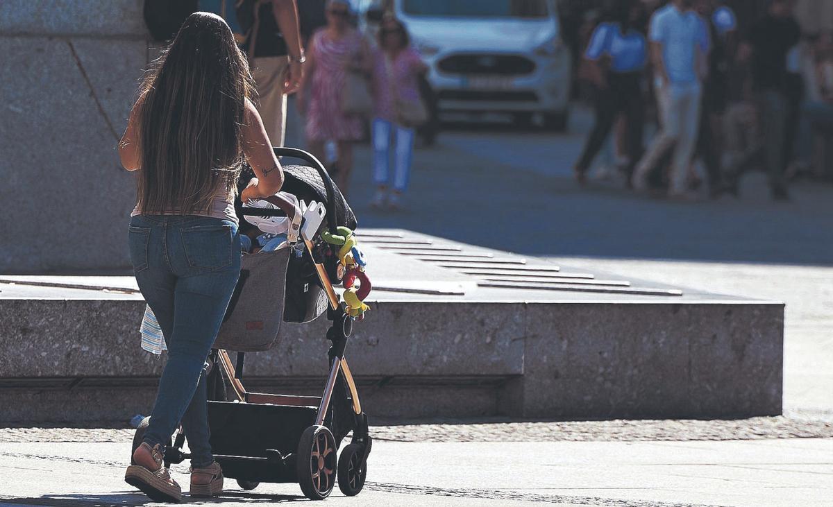 Una mujer pasea a un bebé por la calle.