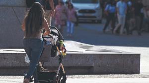 Una mujer pasea a un bebé por la calle.