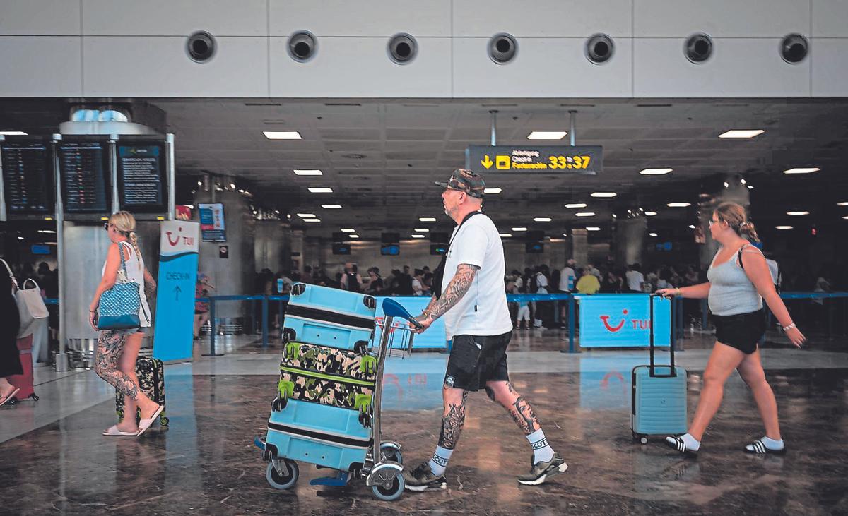 Turistas arrastran sus maletas y carros por las instalaciones del aeropuerto Tenerife Sur.