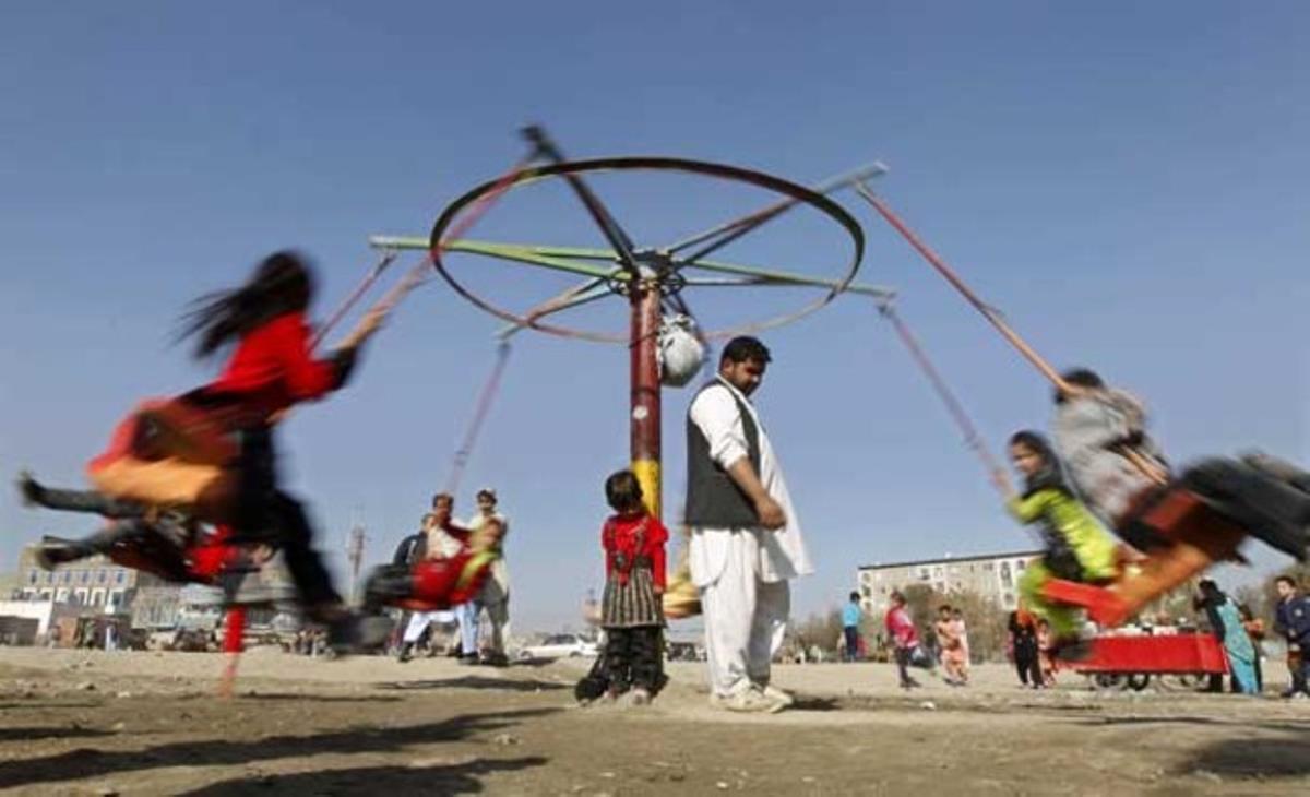 Nens juguen en una nòria a Kabul (Afganistan).