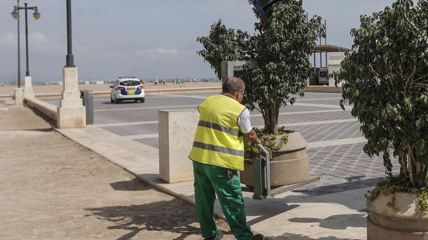 Un operario coloca un macetero en el paseo marítimo.