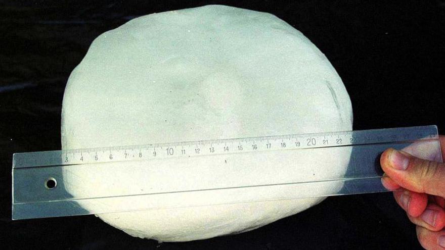Una persona mide con una regla un trozo de hielo caído del cielo, en una foto de hace 20 años.