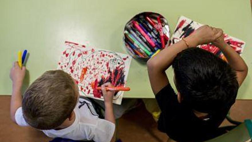 Dos niños pintan en sus cuadernos.