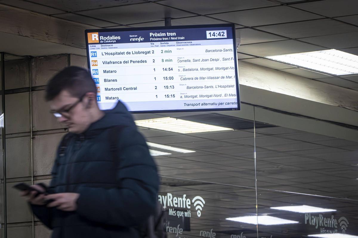 Un viajero consulta en su móvil los horarios de los trenes.